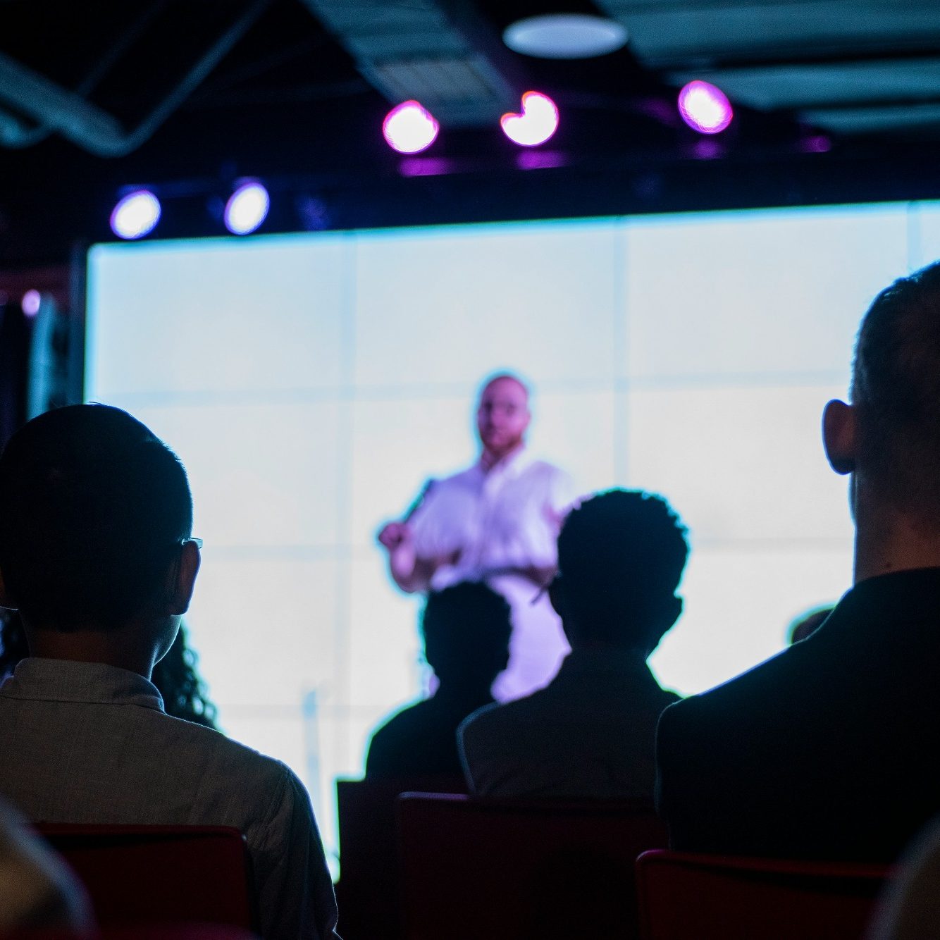 Une personne s'exprimant sur scène devant un public attentif.